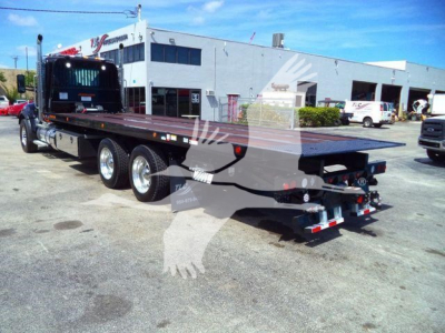 Kenworth T880 rollback truck with long flatbed and dual rear axles, rear view showing trailer hitch and rear lights.
