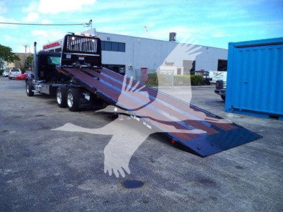 Kenworth T880 rollback truck with a lowered flatbed inservice straight-on view showing hydraulic ramp and rear wheels