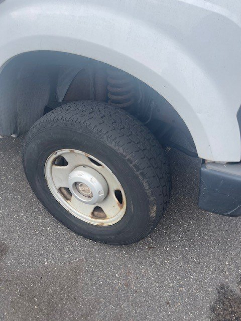 Front left wheel and fender of a Ford Super Duty F-250 SRW; wheel with steel rim, tire, suspension components visible.