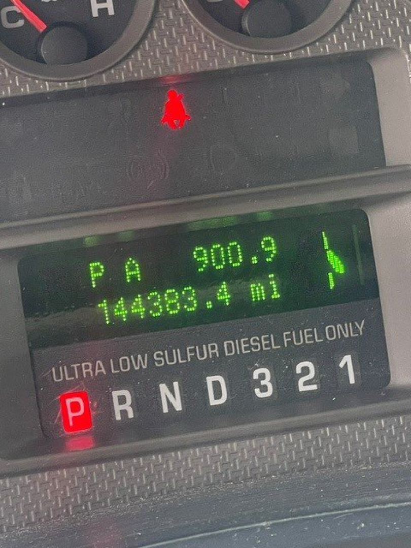 Dashboard of a Ford F-250 showing gear selector P, PRND321 along with a digital display reading 900.9 miles and 144,389.4 miles and a red parking brake indicator. Text: ULTRA LOW SULFUR DIESEL FUEL ONLY.