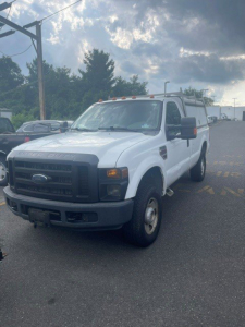 Ford F-250 Super Duty SRW pickup truck white front-left view showing bumper, grille, headlights, and side mirror.