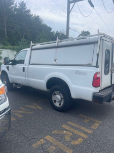 Ford Super Duty F-250 SRW pickup truck with white utility/storage topper, visible rear and side profile, basic equipment, salvage or used condition