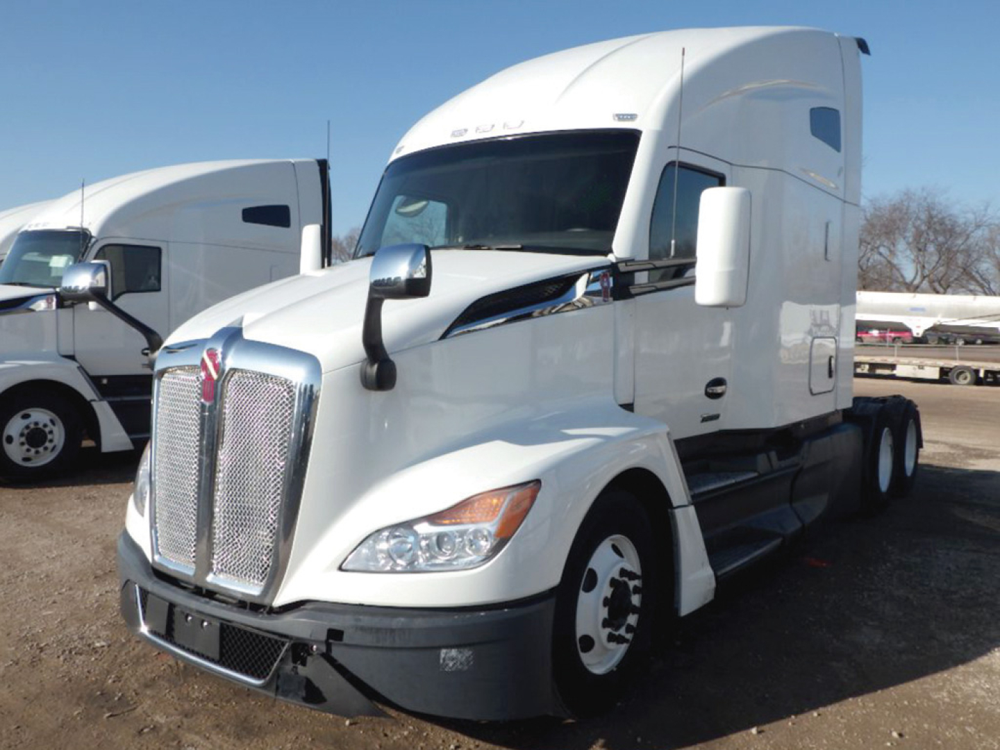Kenworth T680 Next Gen tractor unit in a used truck lot showing front grille and sleeper cab.