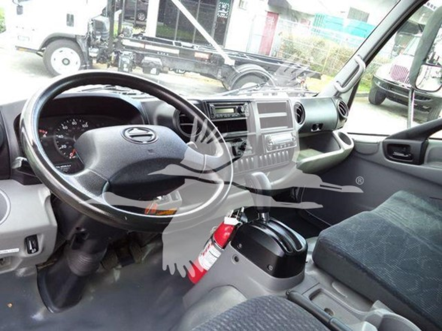 2019 Hino 195 interior showing steering wheel, dashboard, and front passenger area with fire extinguisher mounted near console.