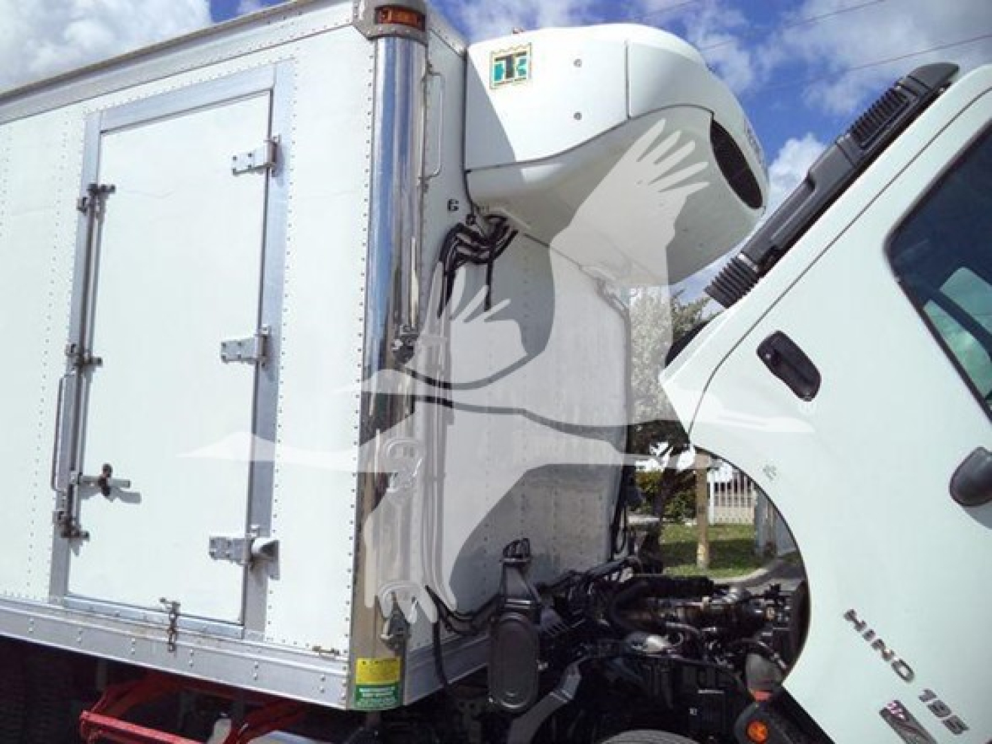 Truck cab and freezer box of a 2019 Hino 195 refrigerated truck, side view showing front cab and insulated cargo box with refrigeration unit on top.