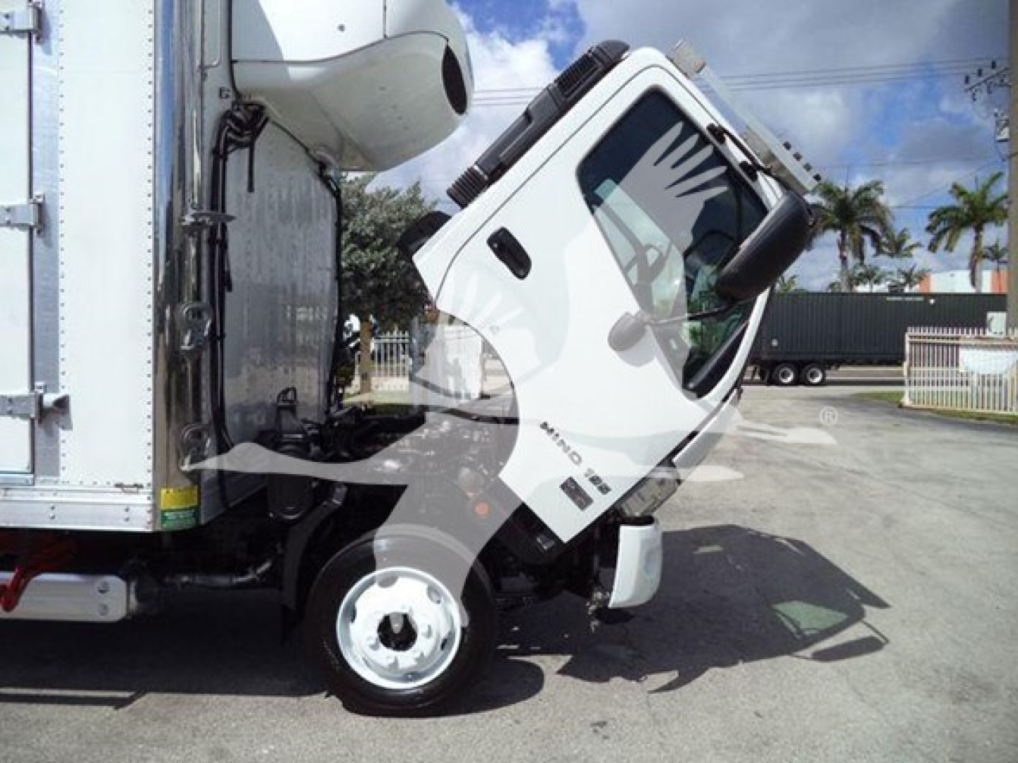 2019 Hino 195 refrigerated truck cab tilted forward showing front wheel and side of cargo box with VIN and stock info overlaid.