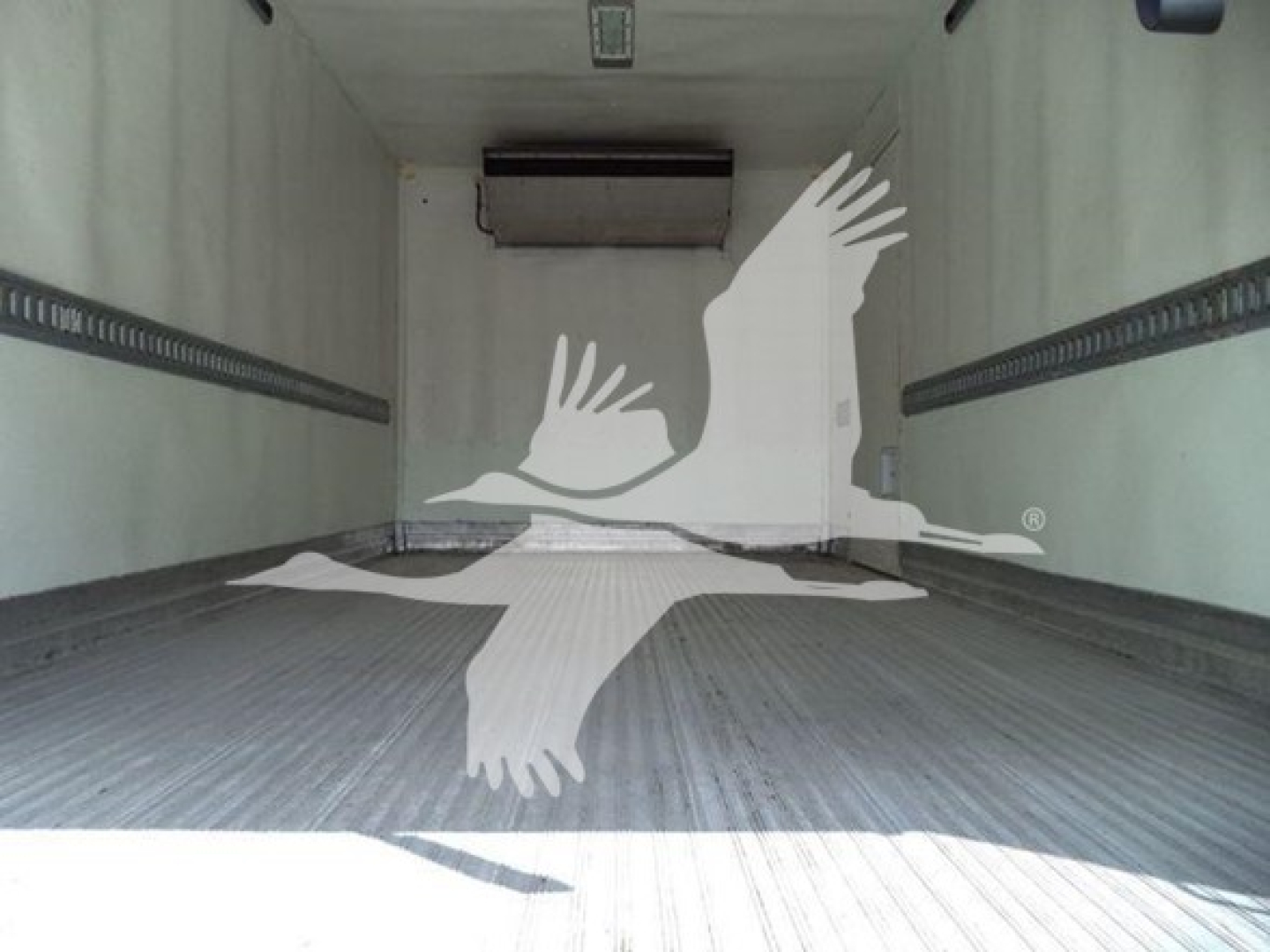 Truck cargo area showing empty refrigerated box with ribbed floor and ceiling mount, inner walls, and a hanging unit at the front.
