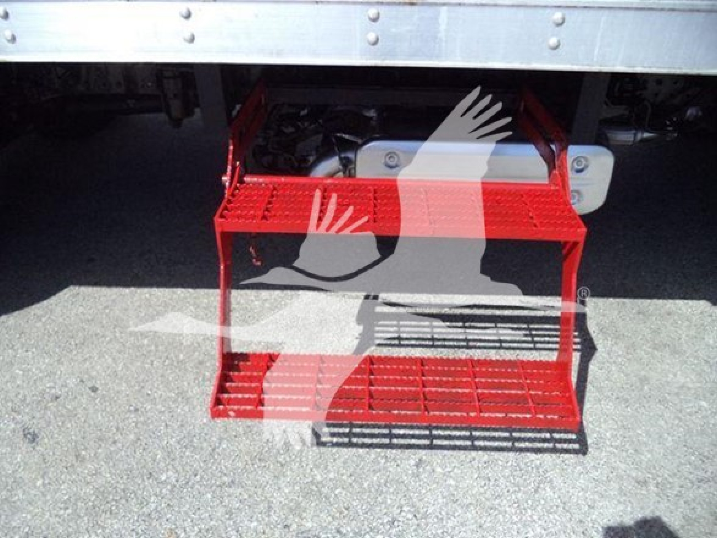 Step platform attached under a refrigerated truck with red metal steps and grip surface.