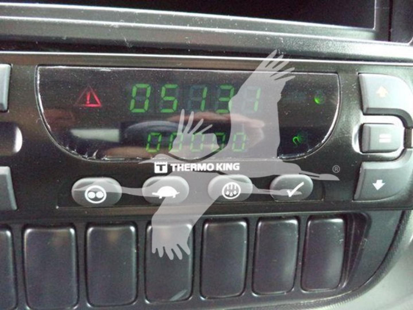 In-dash digital gauge cluster showing green LCD numbers and Thermo King control panel in a refrigerated truck cab.