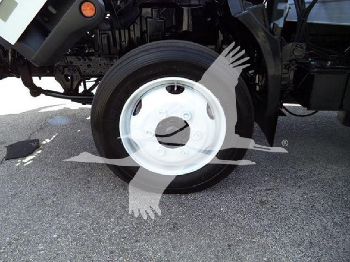Flat side view of a Hino 195 front wheel well with white wheel and tire showing; no visible text on tire, vehicle side panels, or labels.