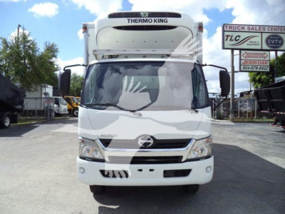 Front view of a white 2019 Hino refrigerated truck with Thermo King unit on top; visible logos and dealership signs in the background.