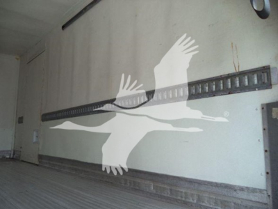 Interior wall of a refrigerated truck with a horizontal double-rail track and some faint text on the wall
