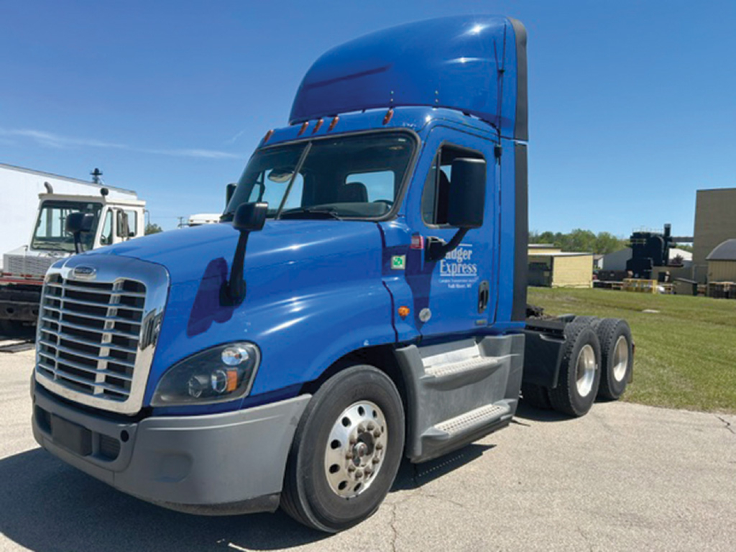Freightliner Cascadia Evolution day cab tractor with blue cab and sleeper, front grille, side steps, and dual rear axles visible.