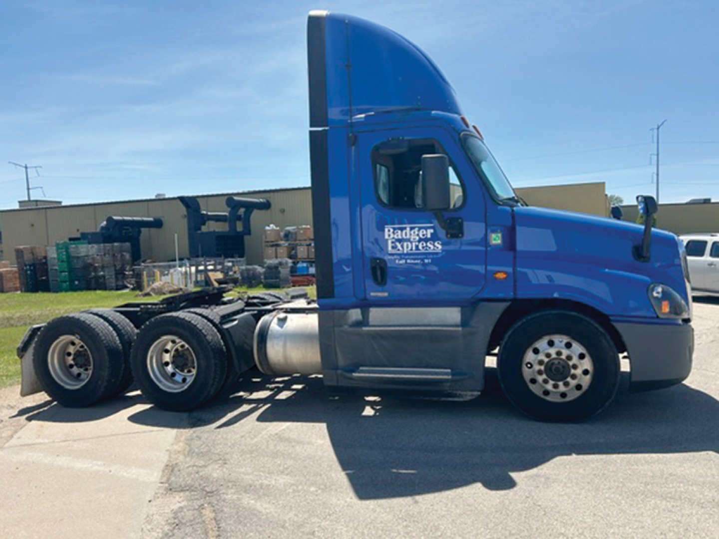 Truck side profile showing blue Freightliner Cascadia Evolution cab with Badger Express logo, dual rear axles, and sleeper cab—06/14 style tractor.