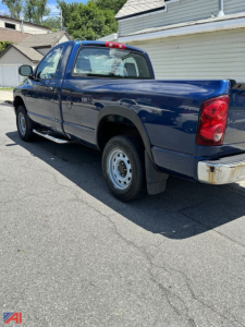2007 Dodge Ram 1500 pickup truck in blue, extended cab, shown from rear-side angle in a driveway.