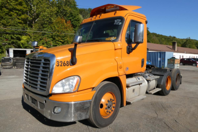 Truck cab front-left view of a orange Freightliner Cascadia 125 semi-truck tractor; visible front grille, bumper, hood, windshield, and side mirror.