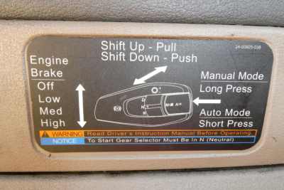 Label on Freightliner Cascadia gear selector with Shift Up - Pull, Shift Down - Push instructions, Manual Mode Long Press, Auto Mode Short Press, Engine Brake Off Low Med High, warning notice about gear selector neutral.