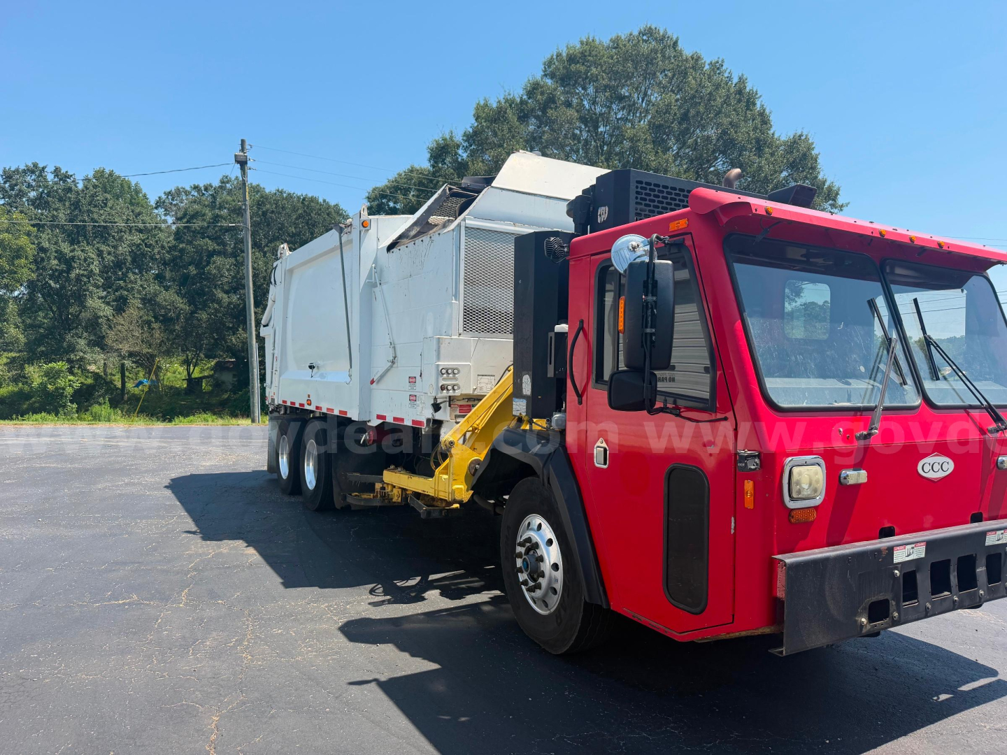Red and white crane carrier truck rear view showing garbage body and lifting mechanism.