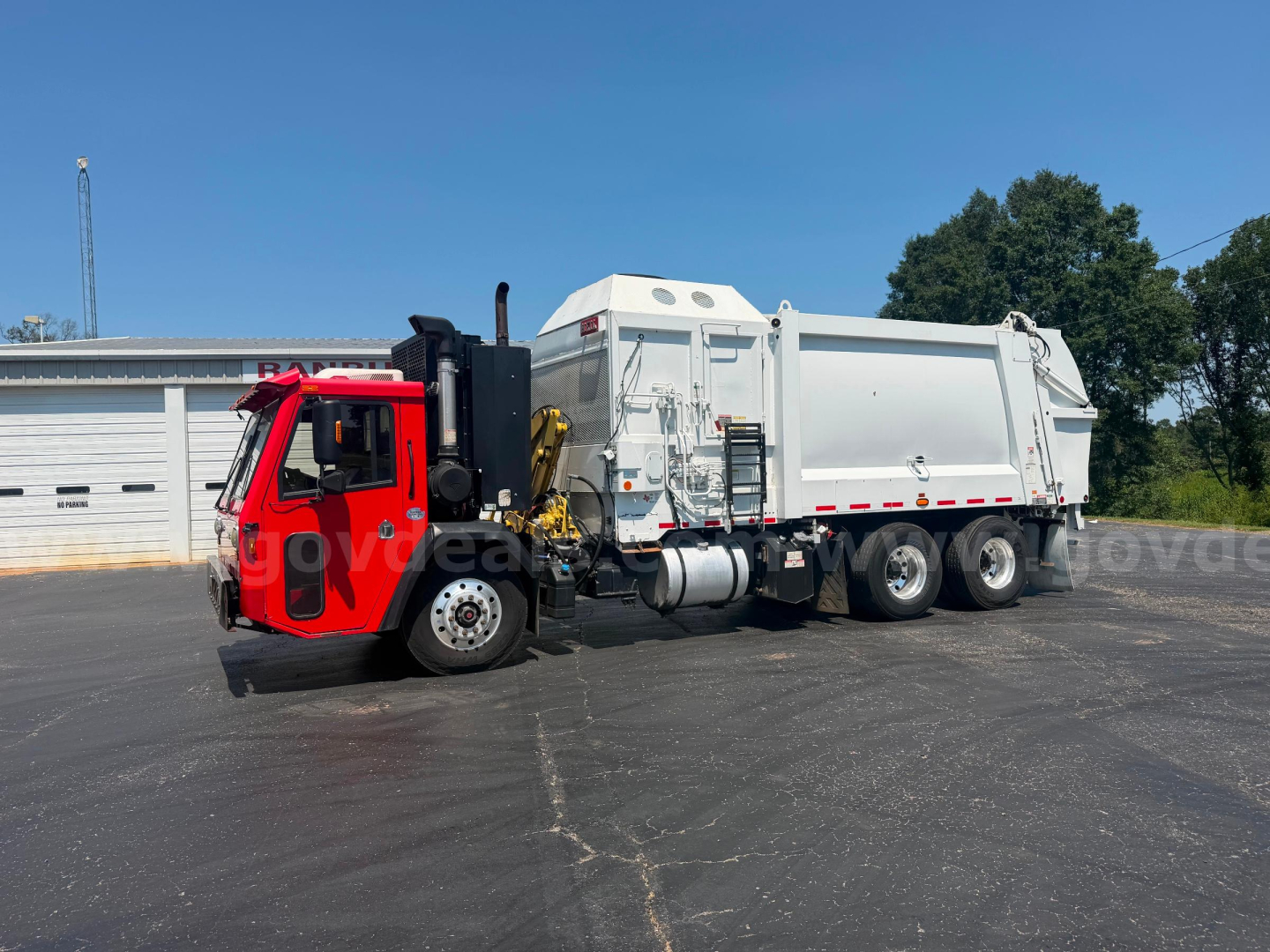 Truck in service bay showing crane carrier ASL and large dump body on a white and red truck chassis.