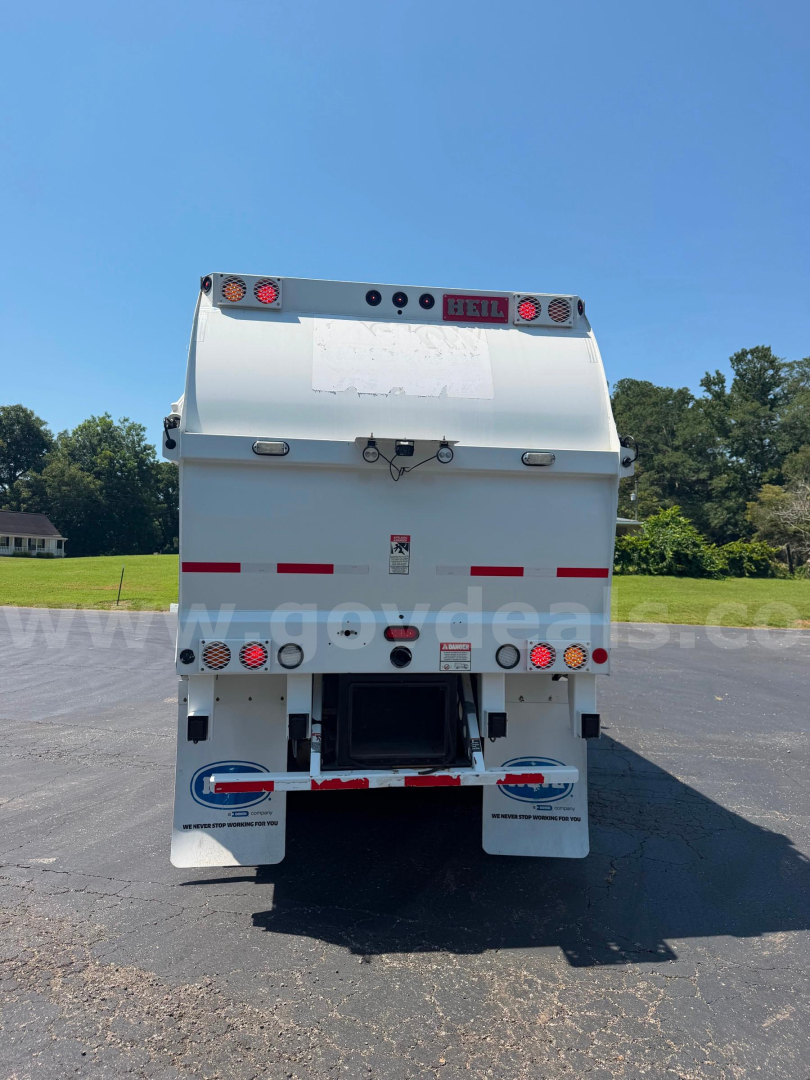 Back view of a white Crane Carrier garbage truck with rear hatch, lights, and reflective red/white strips.