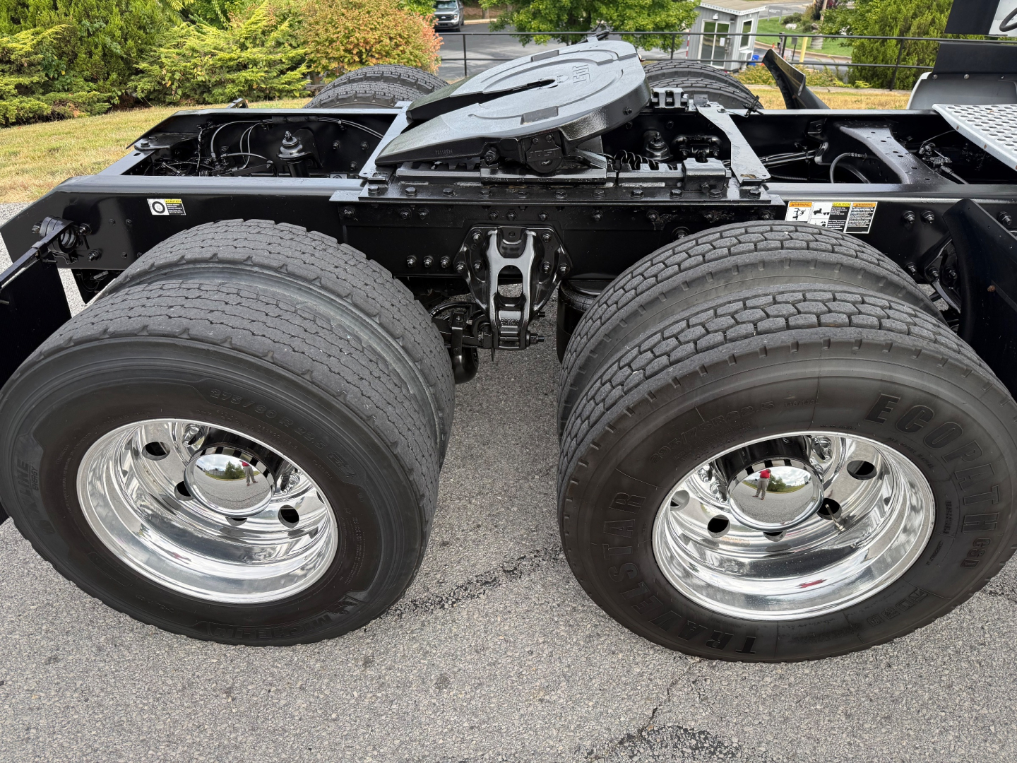 Kenworth T680 chassis showing dual rear wheels and spring suspension with fuel lines and frame, chrome wheel rims visible.