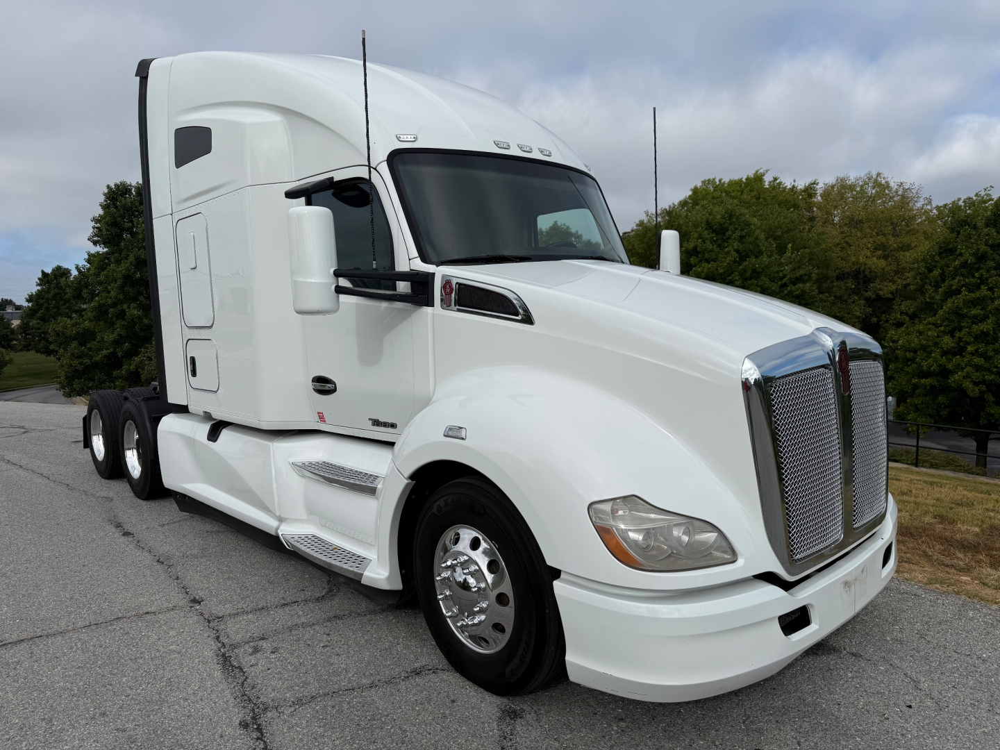 Kenworth T680 tractor with white exterior, side view showing chrome grille, large mirrors, and aerodynamic sleeper cab. No visible text on sides.