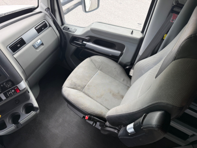 Truck cabin interior of a 2022 Kenworth T680 driver seat and dashboard view showing steering wheel, door panel, and center console.