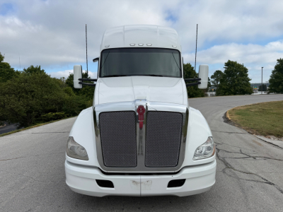 Front view of a white 2022 Kenworth T680 tractor showing large black grille, Kenworth emblem, rectangular headlights, bumper with license plate area, mirrors on both sides.