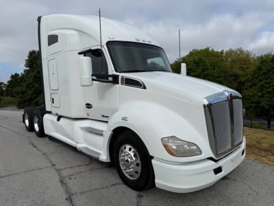 Kenworth T680 tractor with white exterior, side view showing chrome grille, large mirrors, and aerodynamic sleeper cab. No visible text on sides.