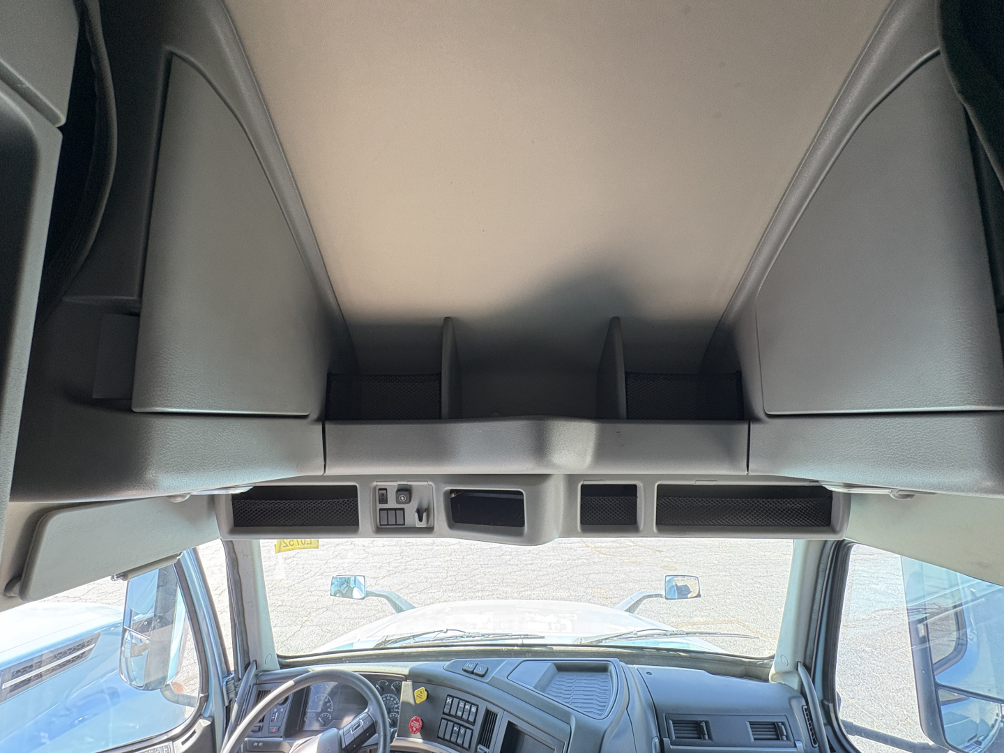 Cab interior of a Volvo VNL truck with overhead storage compartments and windshield view; front dash area visible.