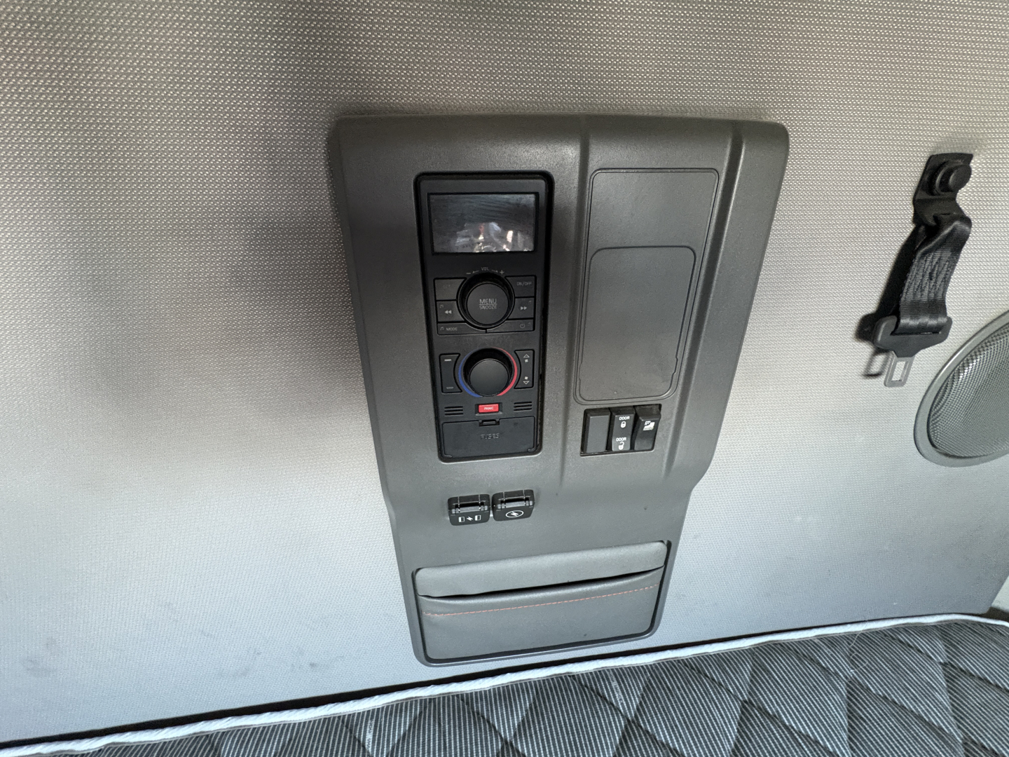 Volvo VNL truck interior control panel and overhead console with switches and small display panel in view.