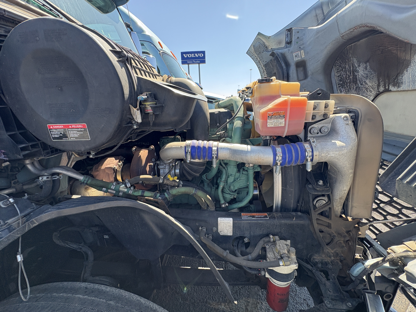 Volvo VNL64T760 engine bay showing diesel engine, coolant reservoir, hoses, and surrounding components.