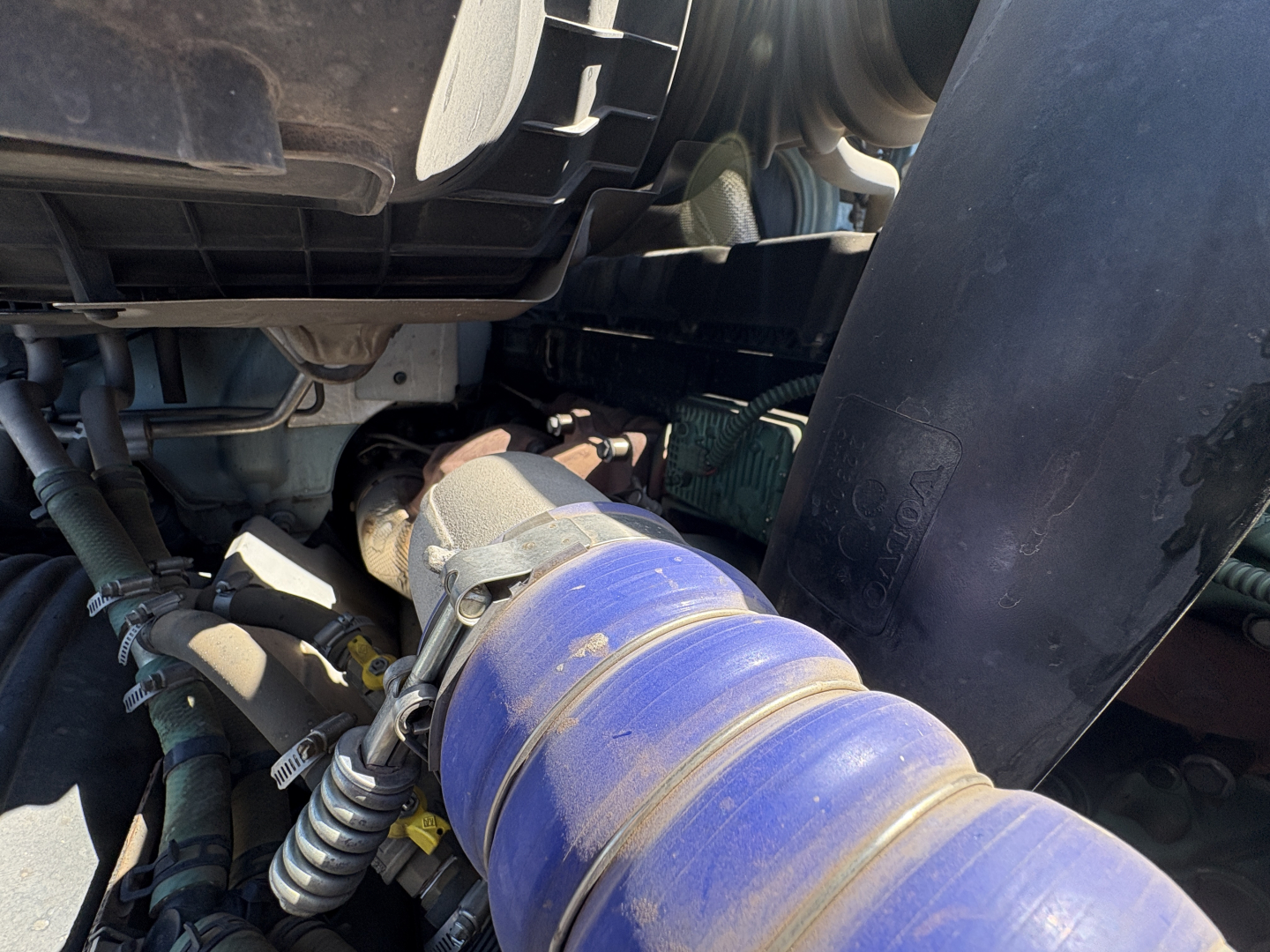 Volvo VNL64T760 engine bay view showing blue air intake hose and surrounding mechanical components.