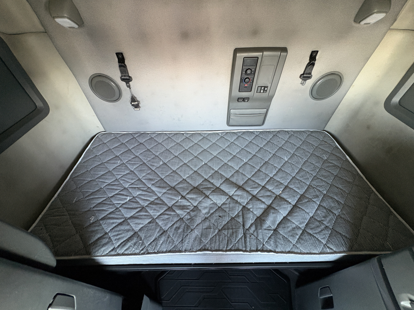 Volvo VNL64T760 sleeper cab interior bunk area with quilted mattress pad and control panel on bulkhead