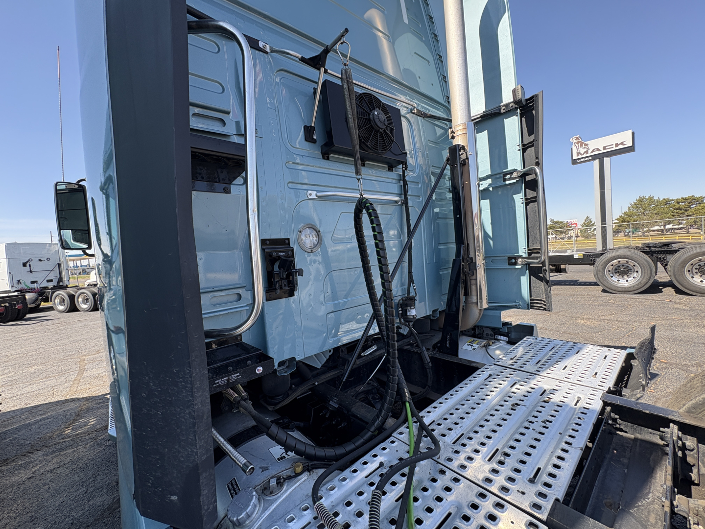 Volvo VNL64T760 truck sleeper cab side with steps and hydraulic lines visible, front of cab and equipment near door.