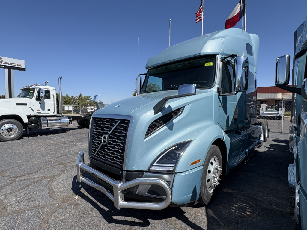Volvo VNL64T760 tractor in blue, front view with grille guard. Visible text includes Volvo emblem and truck styling; no readable labels or fluid specs clearly shown.