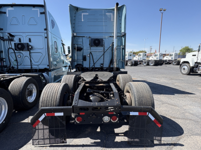 Truck chassis rear view showing fifth-wheel coupling and dual rear axles of a 2022 Volvo VNL64T760 Sleeper tractor with surrounding trucks in a lot.