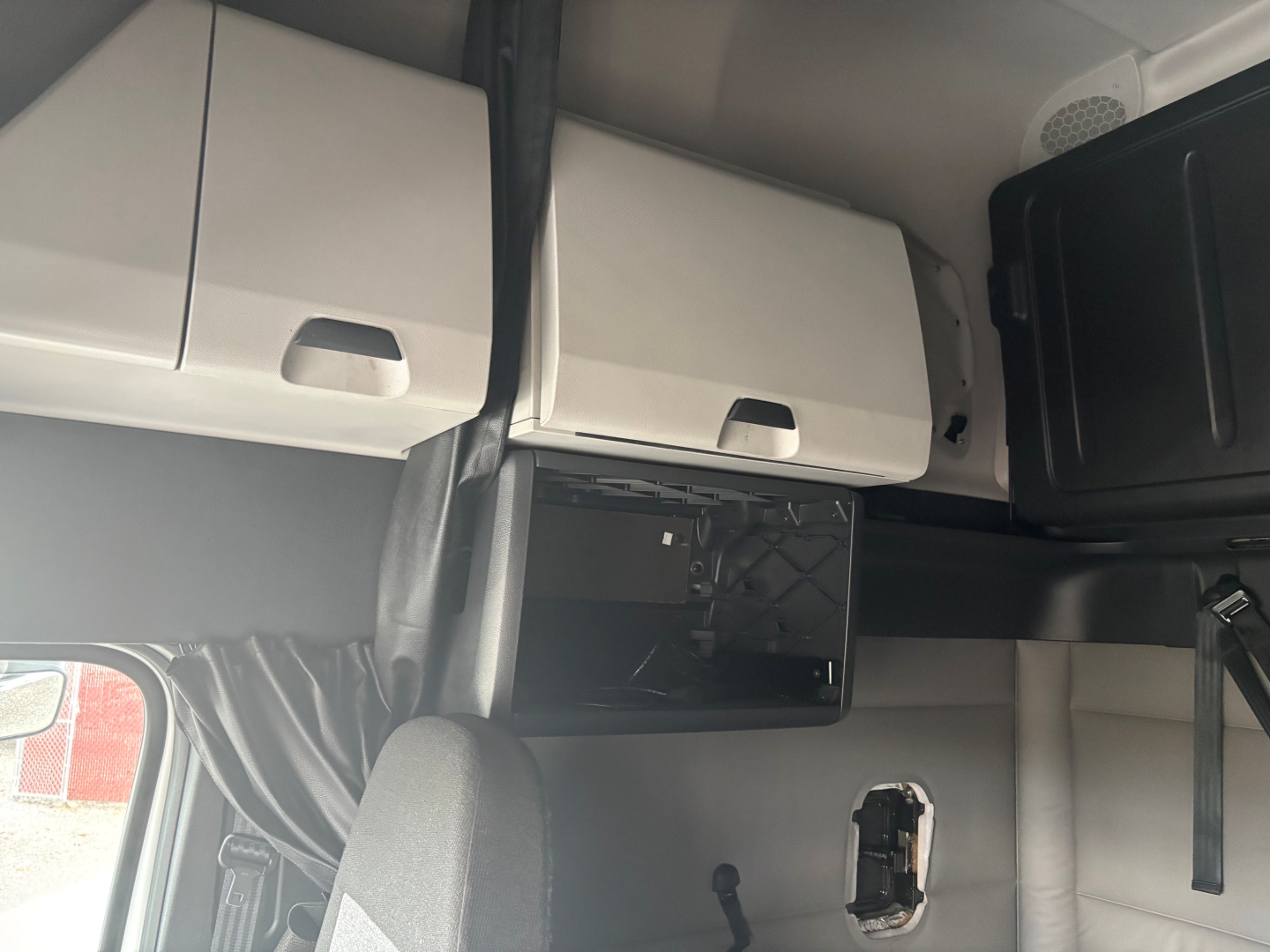 Cab interior of 2021 Freightliner CA-126 sleeper truck showing overhead cabinets and a black dashboard panel.