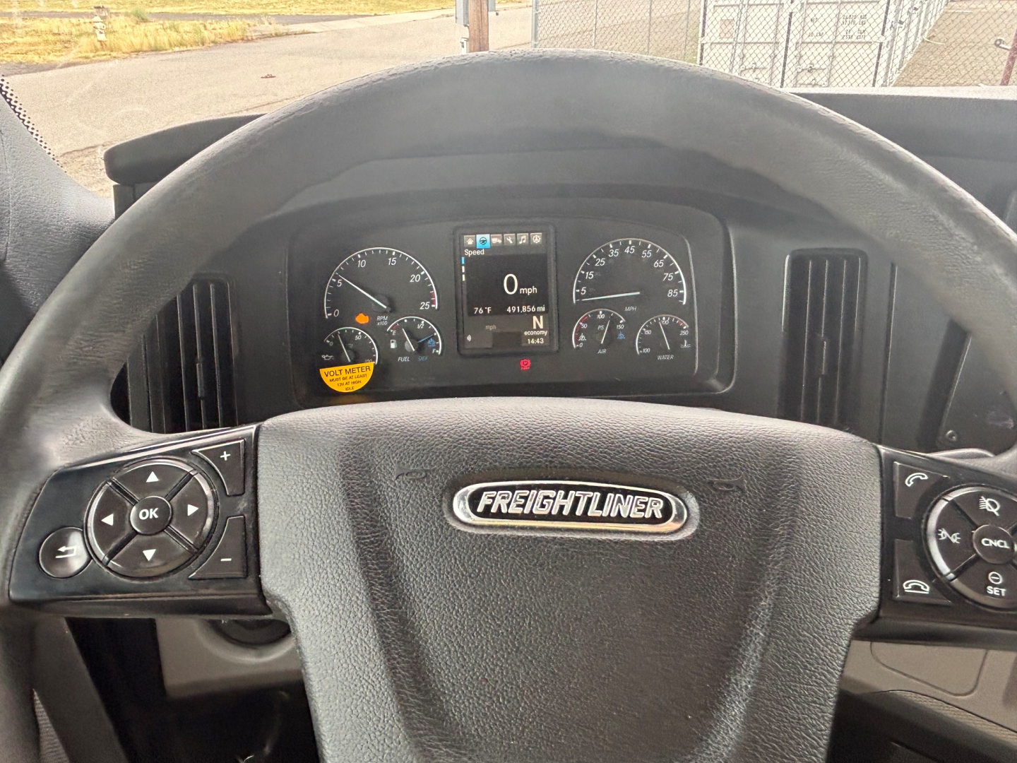 Truck cab dashboard from a 2021 Freightliner CA-126 showing steering wheel with Freightliner emblem and instrument cluster.