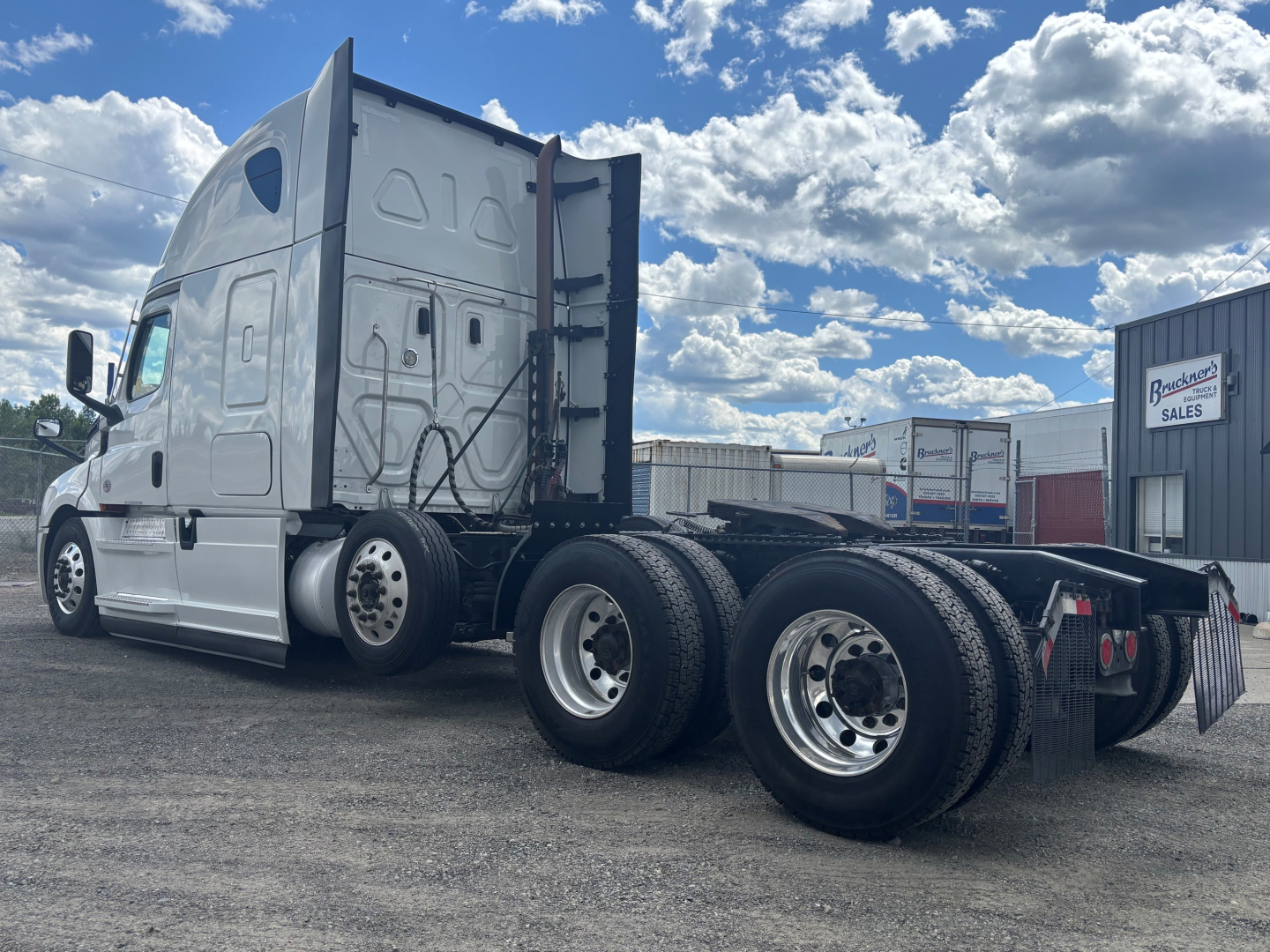 Freightliner CA-126 tractor in side view showing triple rear axles under a gray sleeper cab with clear sky.