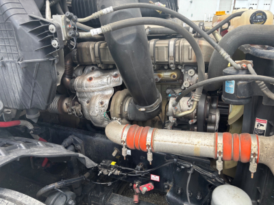 Engine bay of a Freightliner CA-126 with visible turbocharger, hoses, intake, and orange silicone intercooler hose clamp; VIN label and components partially obscured.