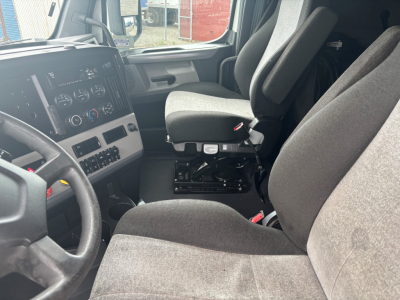 Truck interior showing driver and passenger seats, dashboard with control panel, steering wheel, and center console.