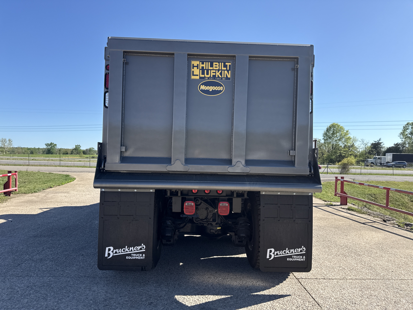 Dump truck bed rear view showing Mack grain-free GR84B with Hilbilt Luckin Mongoose logo, stock mud flaps, and mudflaps, VIN visible on doors