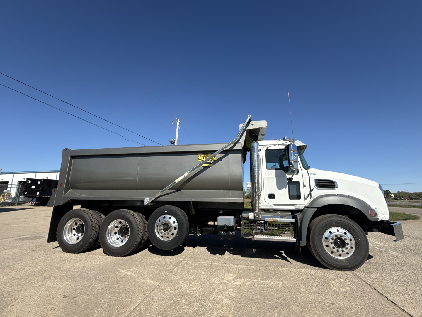 Dump truck side profile showing Mack GR84B with gray dump body and white cab.