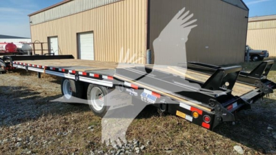 Flatbed trailer in yard showing long deck, rear ramps, and dual axles with white wheels.
