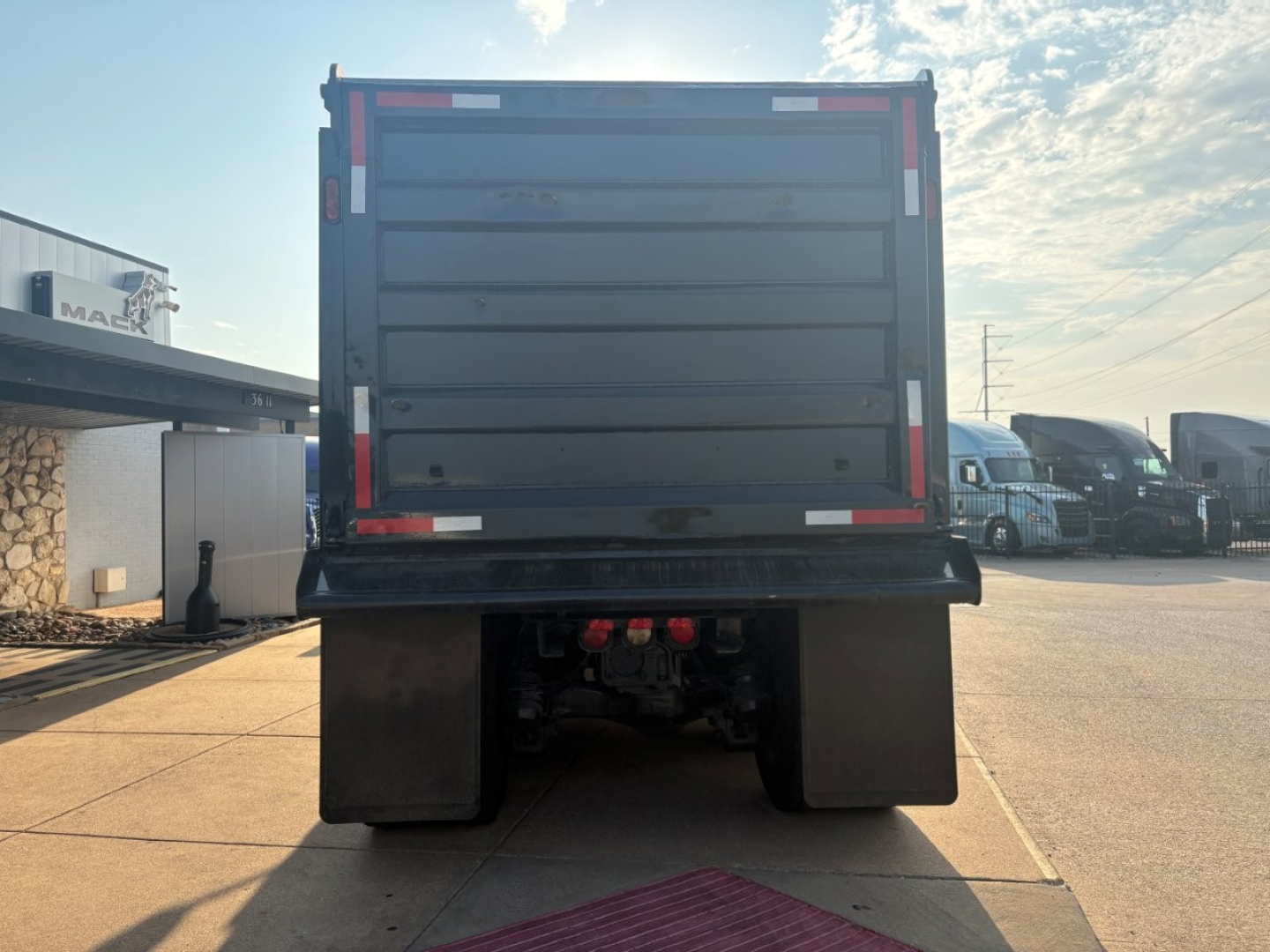 Dump truck bed of a 2021 Mack GR64F shown from rear, with taillight reflectors and mud flaps.