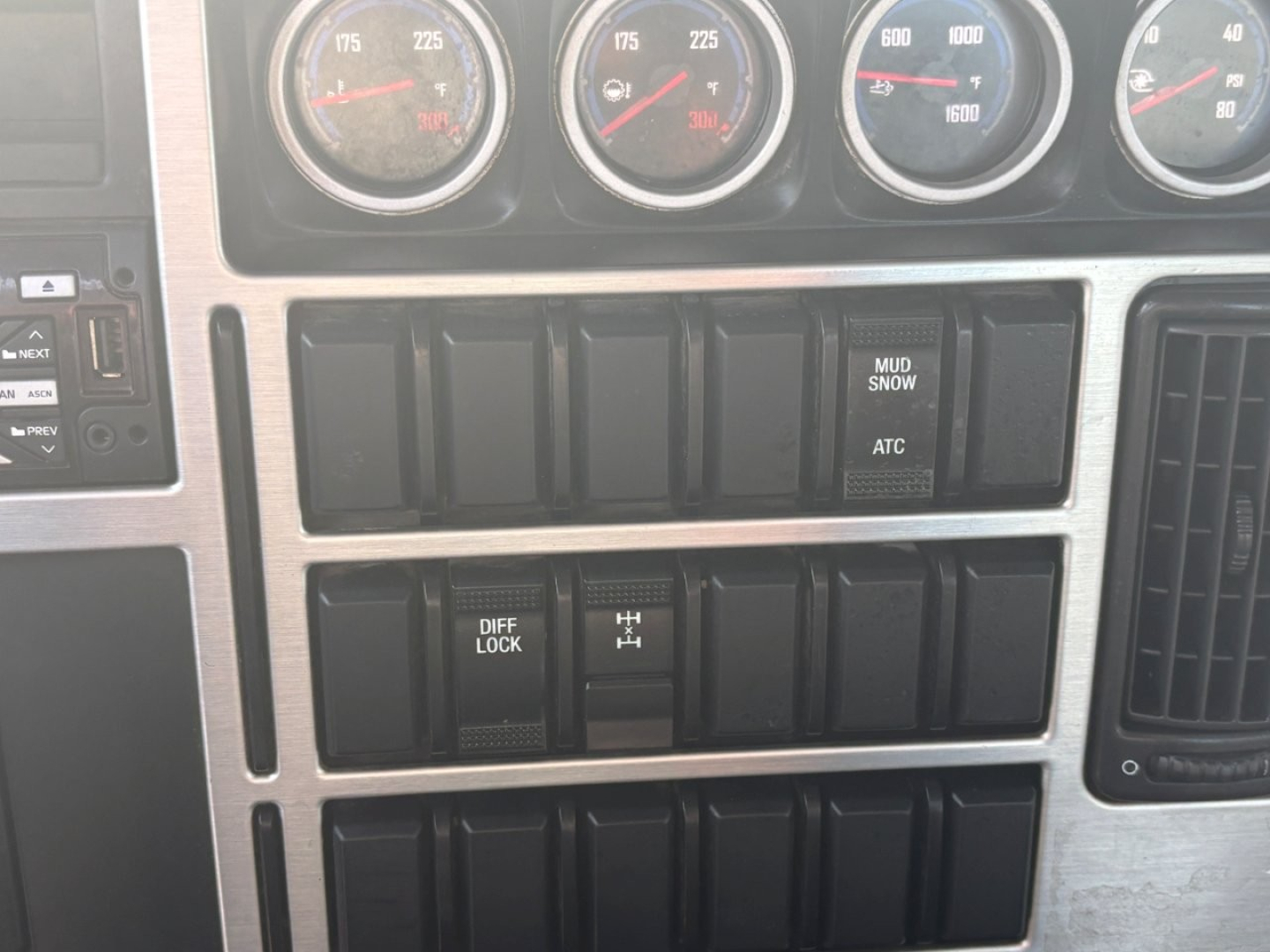 Dashboard area of a 2021 Mack GR64F showing multiple gauges and row of switch panels with labels like DIFF LOCK and H R1. ATC and MUD/ SNOW indicators visible.