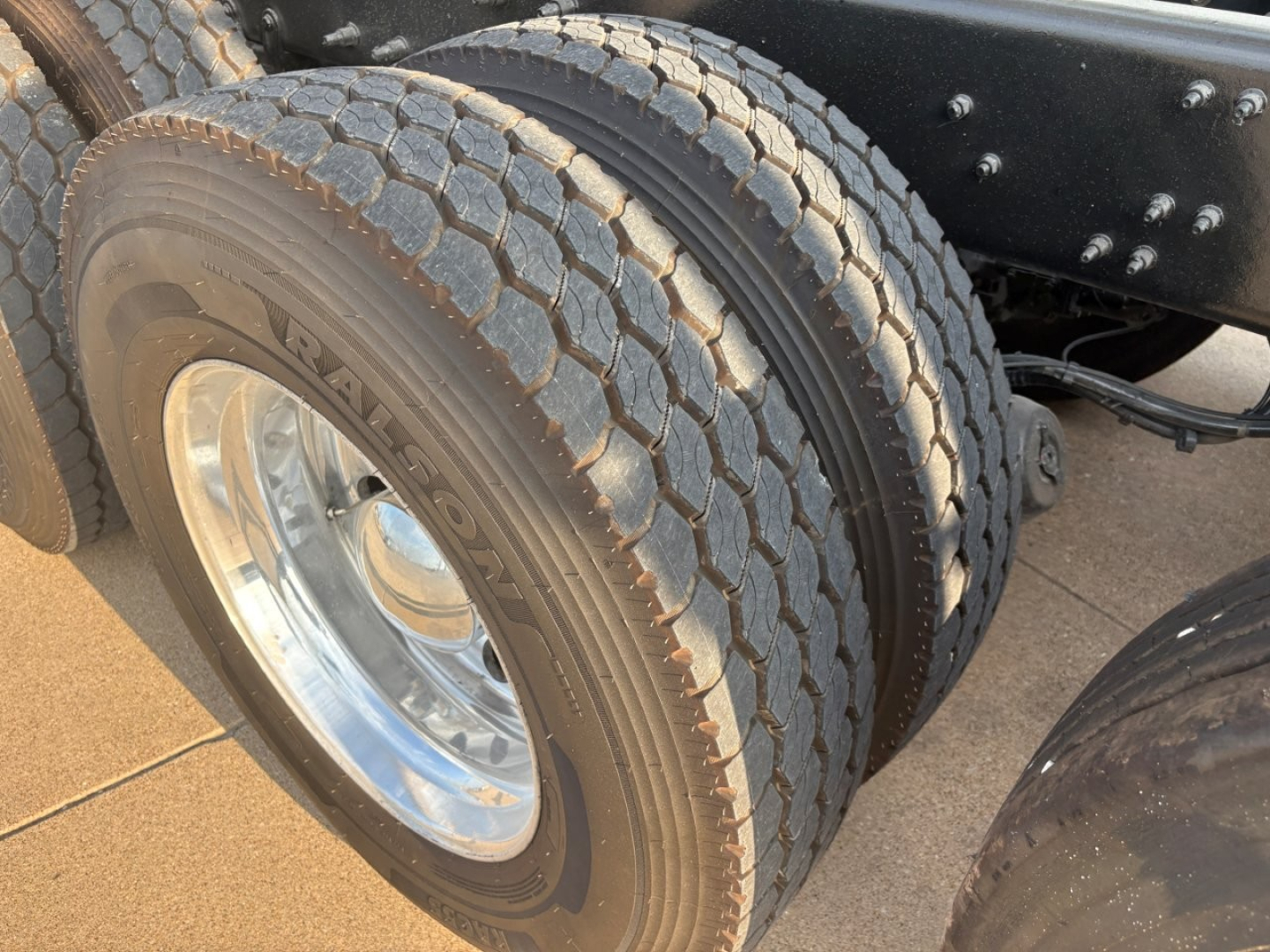 Mack GR64F truck rear dual tires showing tread and polished wheel; chassis frame with bolts.