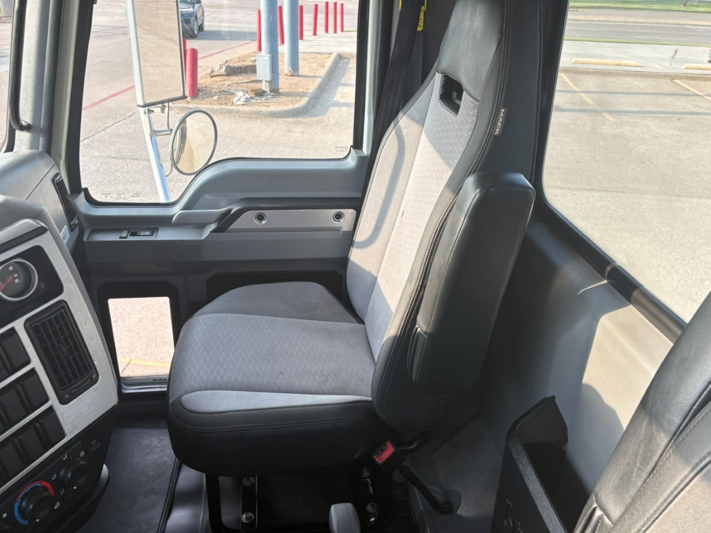 Cargo truck interior showing steering wheel, driver seat, and dashboard area with window and door frame visible.