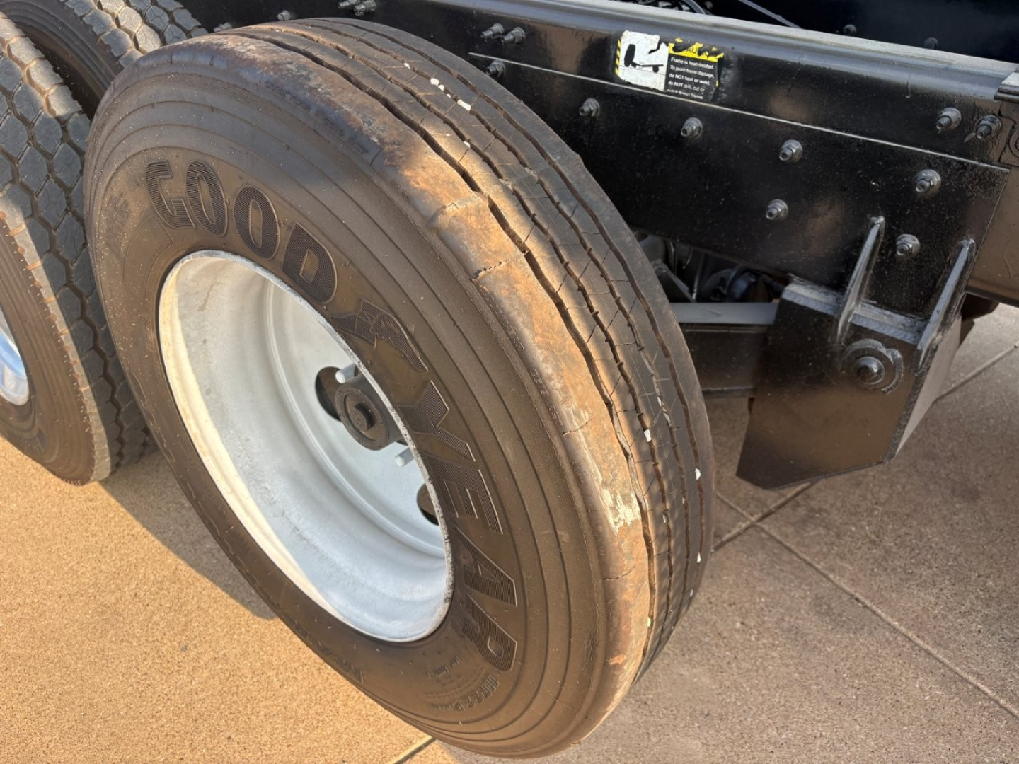 Goodyear tire on Mack GR64F dump truck chassis showing wheel and part of frame with sticker.